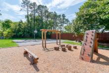 A small park with climbing equipment and a tree line